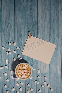 空的问候语或邀请卡模拟了白色的咖啡和棉花糖在木制的蓝色背景。