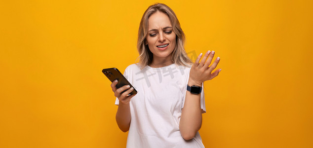一位身穿白色 T 恤、手里拿着智能手机的女士使用黄色背景中的应用程序