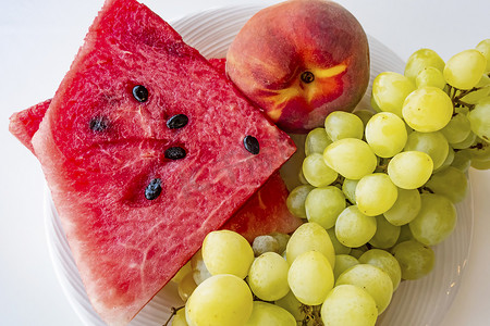 桃子西瓜摄影照片_盘子里的桃子、西瓜和葡萄水果