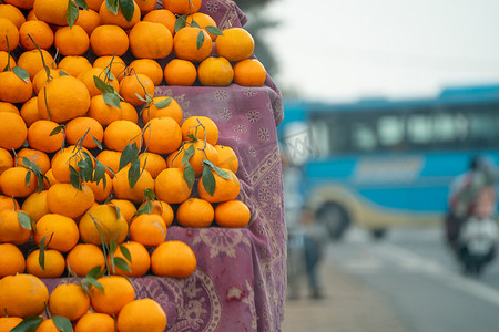 橘子 kinnu 柑橘类水果堆积在路边摊上，展示了农民如何在夏季传统上将这种当地水果作为健康食品在印度出售以供食用和榨汁