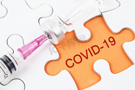 拼图上带有 COVID-19 文本的疫苗和注射器注射。