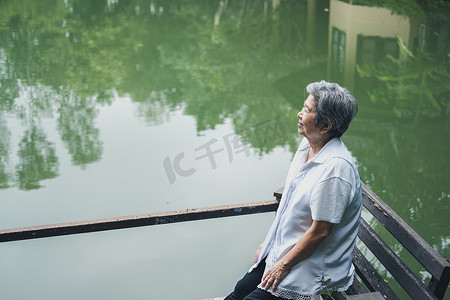 池塘边休息的老妇人。