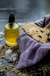 在篮子容器中拍摄 bhakri，在黑色表面上的小玻璃瓶中撒上一些小麦粉和一些食用油。