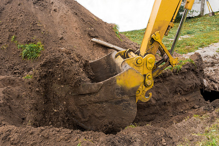 一桶挖掘机或推土机用一堆泥土在建筑工地上挖了一个洞