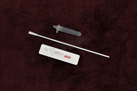 抗原检测试剂盒（ATK）Covid-19在深红色背景上的阳性检测结果，带盒、提取管、棉签