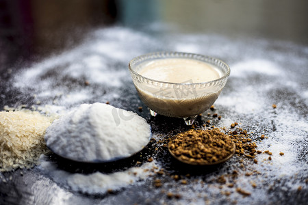 米粉水和胡芦巴/香菜/欧芹种子粉在木质表面上的生发补救措施，并将其粘贴在玻璃碗中，表面涂有一些米粉。