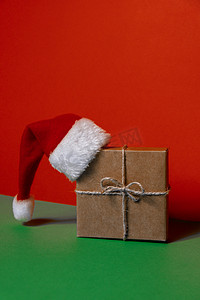 圣诞老人的帽子在纸礼品盒上出现在绿色背景上。