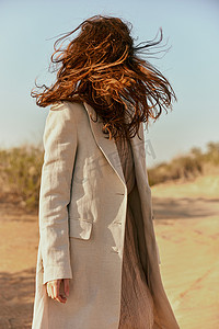 强风吹拂摄影照片_强风吹起一个长着红色长发的女人