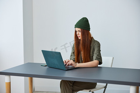 一位戴着帽子坐在办公室笔记本电脑前工作的女性的肖像