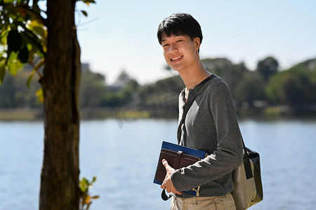 站在湖边的男学生肖像，背景是群山阳光明媚的风景。