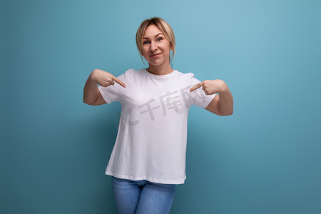 金发年轻女士，带 T 恤模板，用于在带复制空间的工作室背景上插入商业信息
