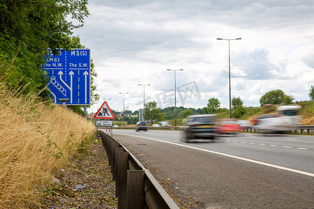 道路指示牌摄影照片_驶过英国高速公路标志的车辆