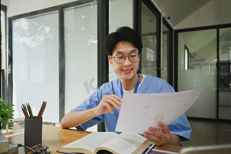 考试准备摄影照片_微笑的男医学生阅读书籍，准备在图书馆参加大学考试。