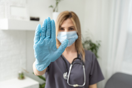 一位戴着防护面具和白色背景医用手套的传染病女医生在她面前伸出了手。
