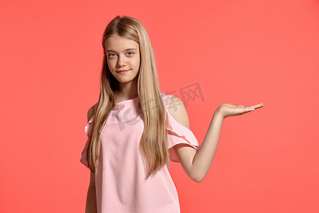 画室背景摄影照片_一个漂亮的金发少女的画室肖像，身穿玫瑰色 T 恤，背景为粉红色。