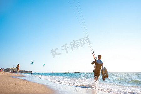 风筝摄影照片_肖像波浪风筝冲浪者带着他的冲浪板和风筝在海滩散步