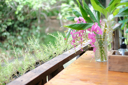 装饰在桌子上的玻璃瓶中的粉红色花朵和绿叶