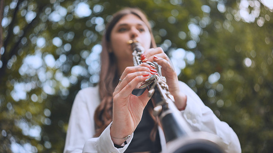 夏天，一个女孩在公园里吹单簧管。