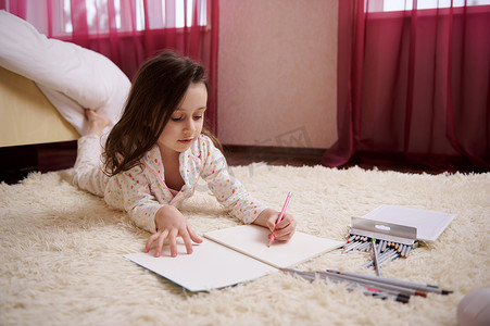 穿着带彩色圆点的时尚睡衣的快乐小女孩，在专辑《儿童爱好教育》中画画