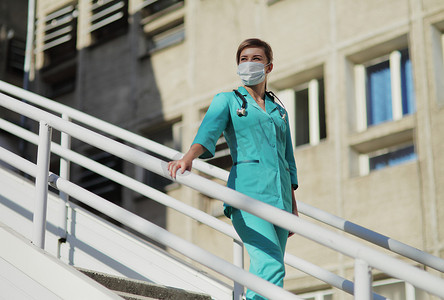 楼梯防护摄影照片_戴防护面罩的女医生或护士走上楼梯