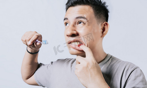 公交故障摄影照片_拿着牙刷牙龈疼痛的人被隔离，人们拿着牙刷被牙龈问题隔离。