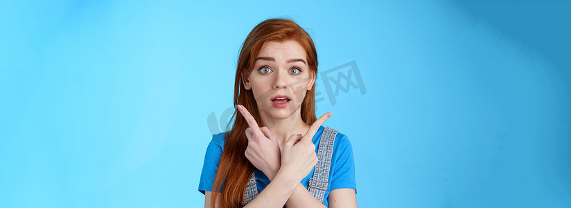 被埋伏的可爱红头发女人询问建议挑选产品，交叉双手指向侧面，显示左右选择，看起来相机想知道不确定，做出决定，蓝色背景