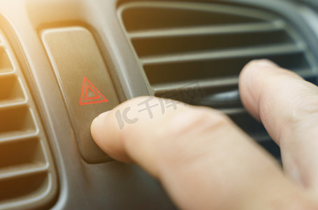 一名男子按下汽车仪表板上的警报按钮。