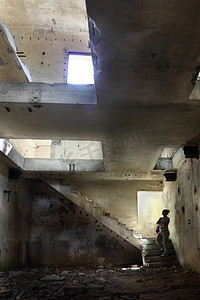 军事工厂摄影照片_一个女人看着建筑物的废墟