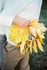 黄色叶子的花圈在女人手中拥抱男人。