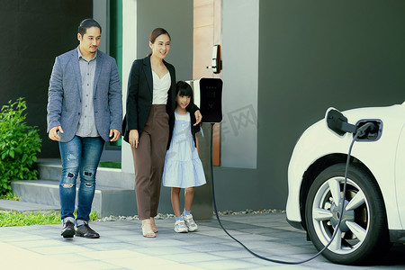 电池家在摄影照片_进步的年轻父母和女儿住在有电动汽车的家里。