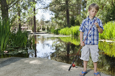 回归25摄影照片_男孩站在湖边调整鱼竿线