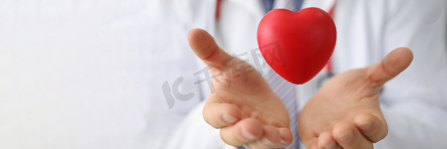 心脏病专家手握空中红色玩具心脏特写