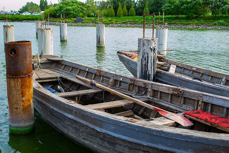 码头上的旧木船在绿水上