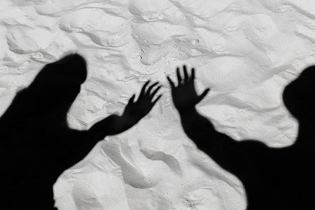 白色沙滩背景上，一个男人和一个影子女孩的黑色剪影向前伸展双臂