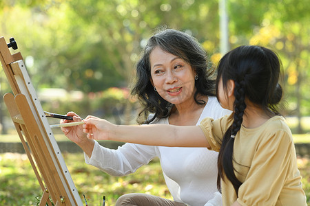 可爱的学龄前女孩喜欢在公园里和祖母一起画画，一起在户外度过休闲周末