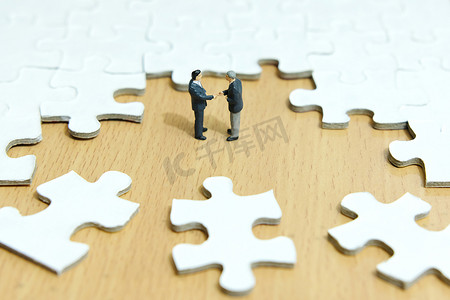 商业战略概念照片 — 微型商人在拼图中心建立握手伙伴关系