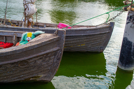 木船河上摄影照片_码头上的旧木船在绿水上