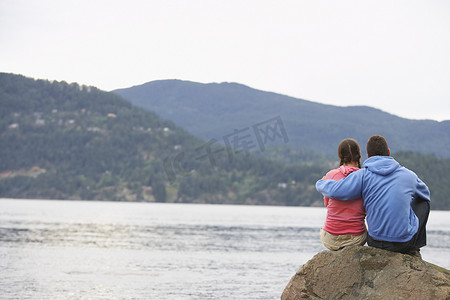 坐在海边摄影照片_坐在海边岩石上的情侣