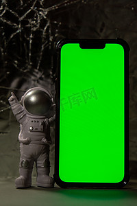 带手机色度键绿色屏幕的塑料玩具人物宇航员为您的广告复制空间。