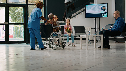 母亲和孩子在医疗机构探望坐轮椅的老妇人