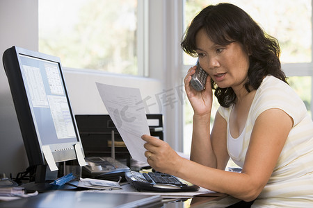家庭办公室的女性使用电话处理文书工作