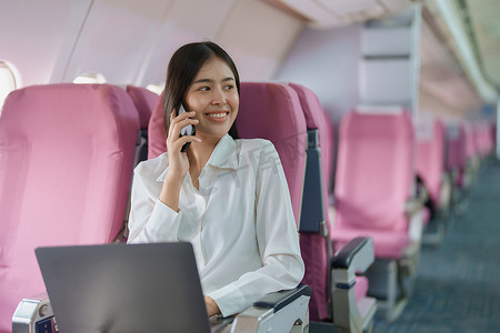 亚洲商务女性乘客坐在商务舱豪华飞机上，同时使用智能手机移动通话或视频会议和旅游概念工作