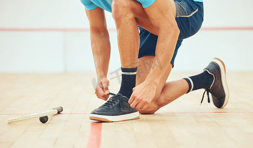 未知的运动壁球运动员在打球场比赛前跪着系鞋带。