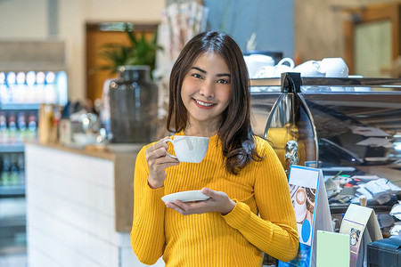 现代咖啡店里拿着一杯咖啡的亚洲年轻女性