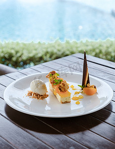 泳池边盘子里的椰子冰淇淋甜点和芒果蛋糕