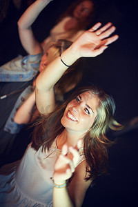 女士们，在夜间派对、音乐节或社交聚会活动中举起手来或跳舞，以欣赏现场音乐、乐队表演或技术朋友狂欢。
