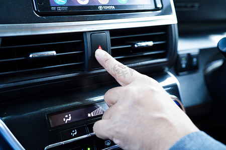 亚洲女司机在汽车仪表板上按下红色紧急停止按钮或恐慌安全按钮。