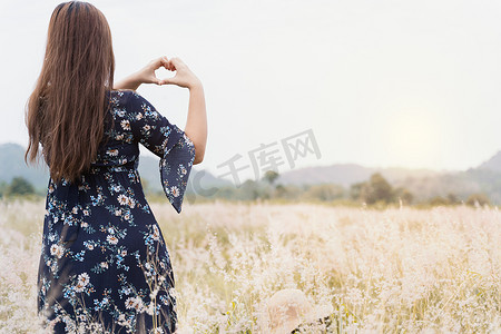 金色的头发摄影照片_阳光下站在草地上的年轻时髦女性的夏日画像