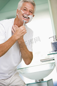 在浴室刮胡子和微笑的男人