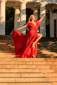 一位身穿红色长裙的女子在日出的映衬下，阳光下散发出明亮的金色光芒。